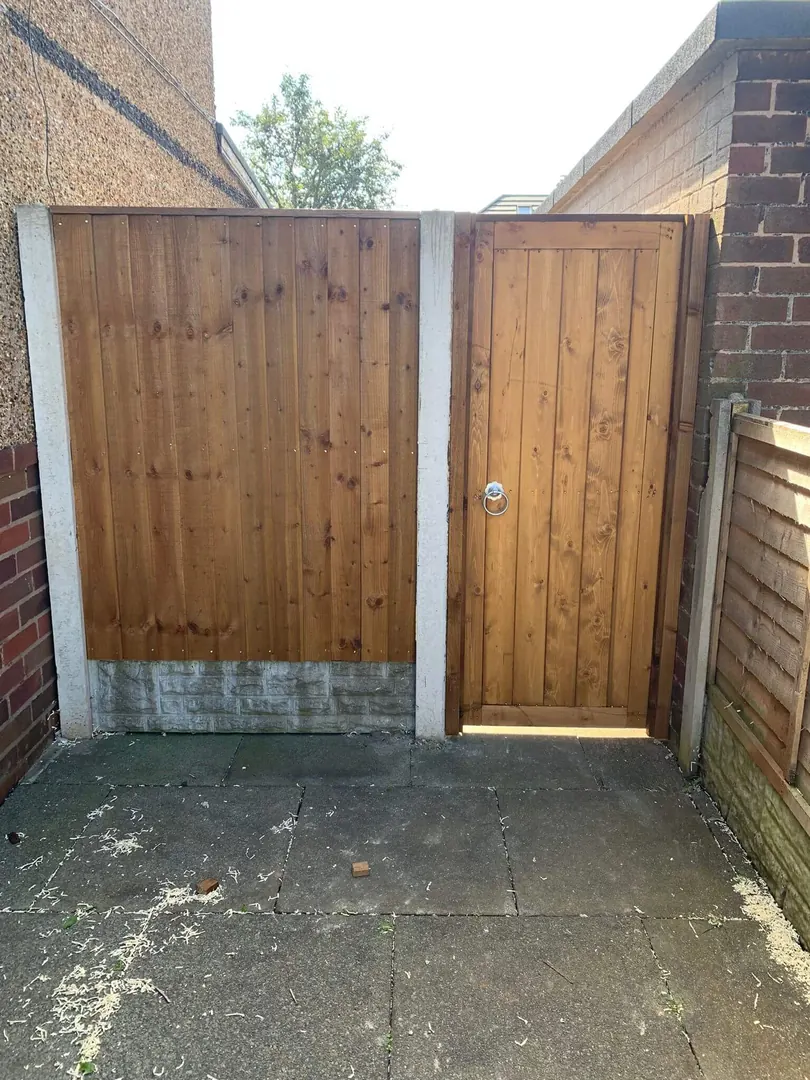 Replacement timber fence panels fitted beside a gate